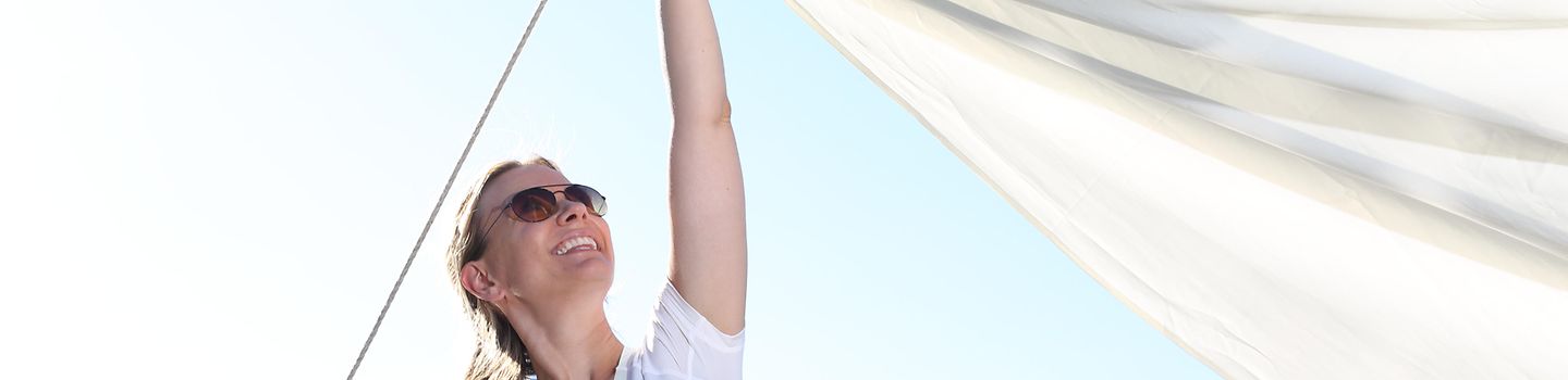 Frau mit Sonnenbrille spannt Sonnensegel