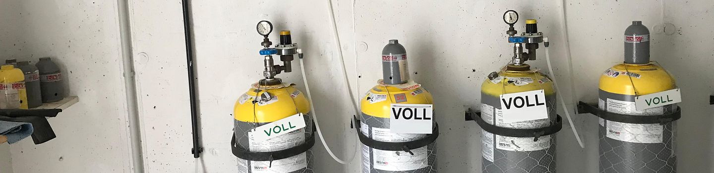 Chlorgasflaschen mit Schildern "voll" vor einer Wand