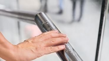 Fluchtwege Hand an einem Handlauf mit Braille-Schrift