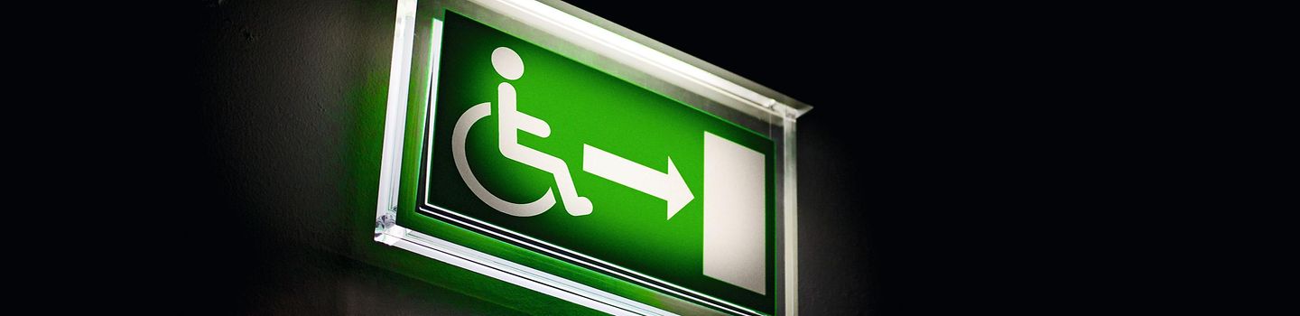 Fluchtwege-Zeichen mit Piktogramm "Rollstuhl" leuchtet im Dunklen.