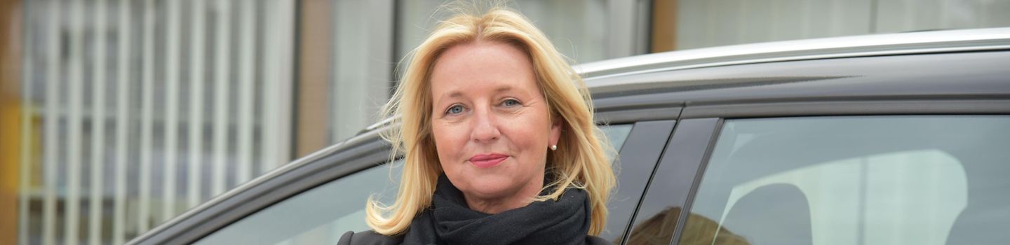 Aufsichtsperson Aufsichtsperson Ruth Giersch steht vor einem Auto und blättert in Unterlagen.