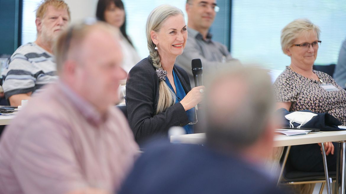 Teilnehmende des BGW trialogs diskutieren im Saal - eine hält ein Mikrofon in der Hand.