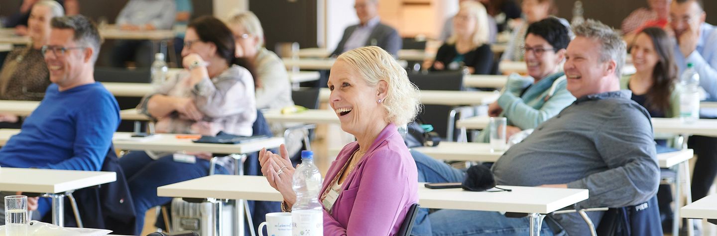 BGW trialog 2022 Saalansicht von vorne - die Teilnehmenden lachen.