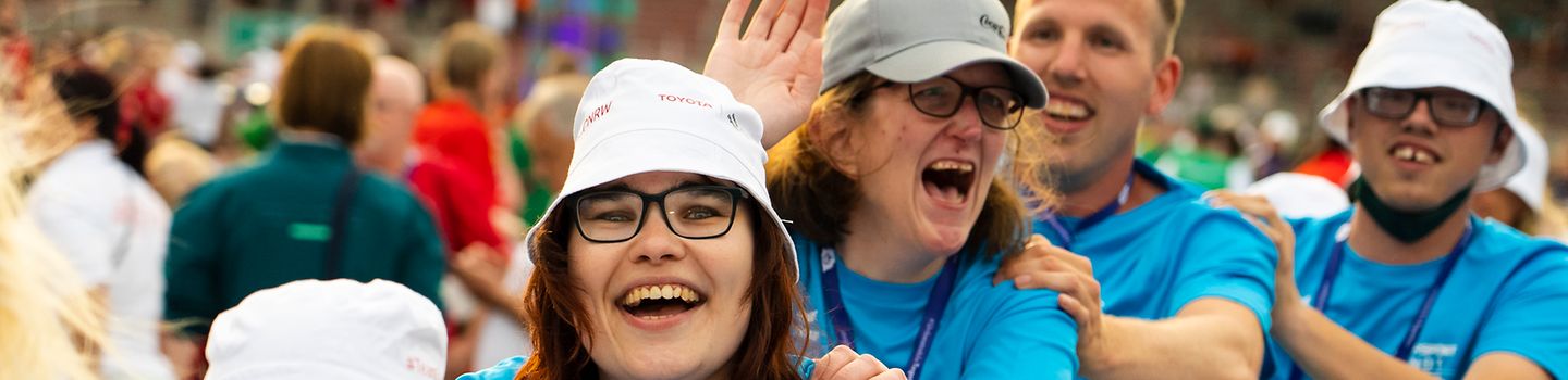 Special Olympics Sommerspiele 2022 - Team in blauen Trikots aus Athletinnen und Athleten feiert fröhlich in einer Polonese die Eröffnung der Spiele
