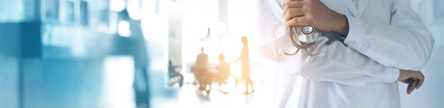 Eine Person in weißer Arztkleidung ist im Anschnitt zu sehen. Sie hält ein Stethoskop in der Hand. Im Hintergrund ist ein Krankenhausflur angedeutet.