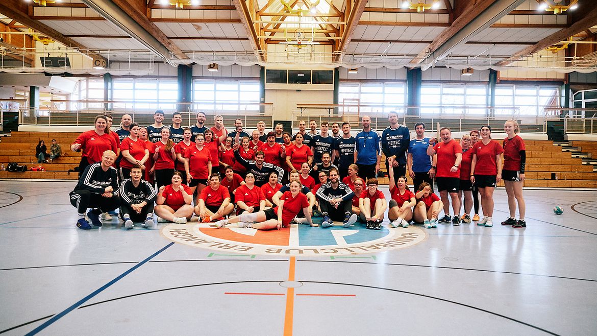 Die gesamte Handballmanschaft sitzt und steht in der Halle des Handballclubs Erlangen.