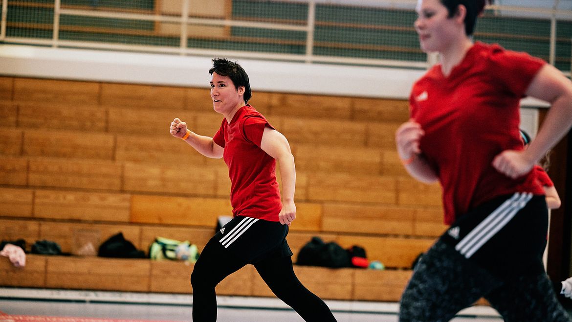 Gaby Grzonkowski läuft mit einer Teamkollegin über das Trainingsfeld. Sie ballt eine Faust und lächelt.