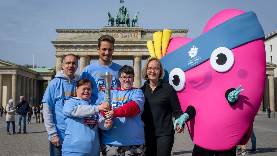 Special Olympics World games 2023 - Einkleidung Athlet Athletin Alessia Schmidt steht lächelnd in roter Trainingsjacke zwischen vier weiteren Sportlern in Rot.