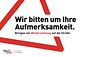 Kampagnenmotiv der Initiative #mehrAchtung: Rotes Warndreieck mit der Aufschrift "Wir bitten um Ihre Aufmerksamkeit" und dem Kampagnen-Stichwort #mehrAchtung
