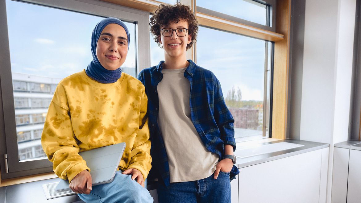 Zwei Frauen stehen lächelnd vor einem Fenster in einem Büro