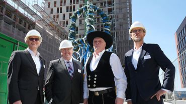 Die vier Männer stehen vor dem Richtkranz auf der Baustelle in der HafenCity
