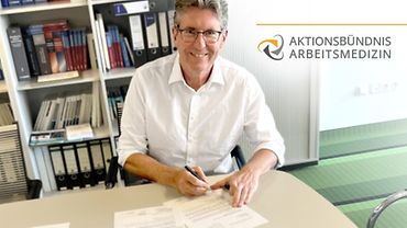 Univ.-Prof. Dr. med. Thomas Kraus Porträt Prof. Kraus, der am Schreibtisch sitzt und Briefe unterschreibt.
