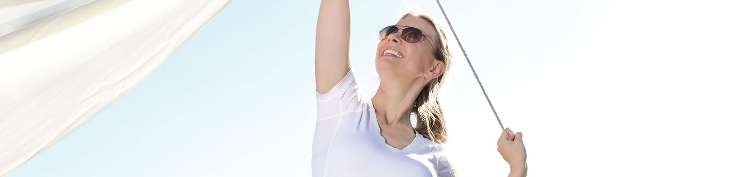 Eine Frau mit Sonnenbrille vor blauem Himmel hält eine Leine in der Hand - an der Leine ist ein weißes Stück Stoff aufgehängt.