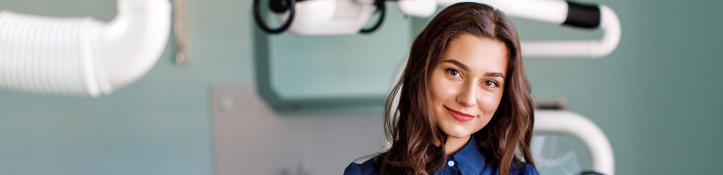 Young doctor in a dental clinic. Portrait of young female doctor dentist with digital tablet in dental office Junge Frau steht im Behandlungszimmer einer Zahnarztpraxis und hält ein tablet im Arm.