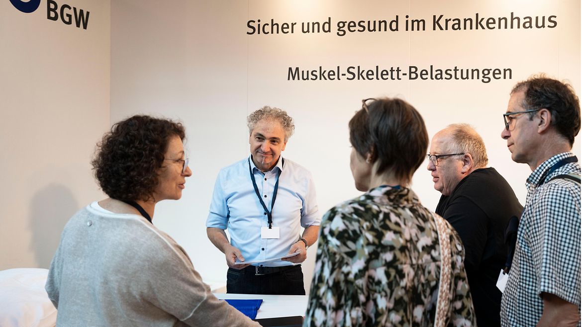 Fünf Menschen stehen um einen Messestand und unterhalten sich.