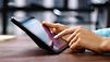 Frauenhände tippen auf das Touchscreen eines tablets.
