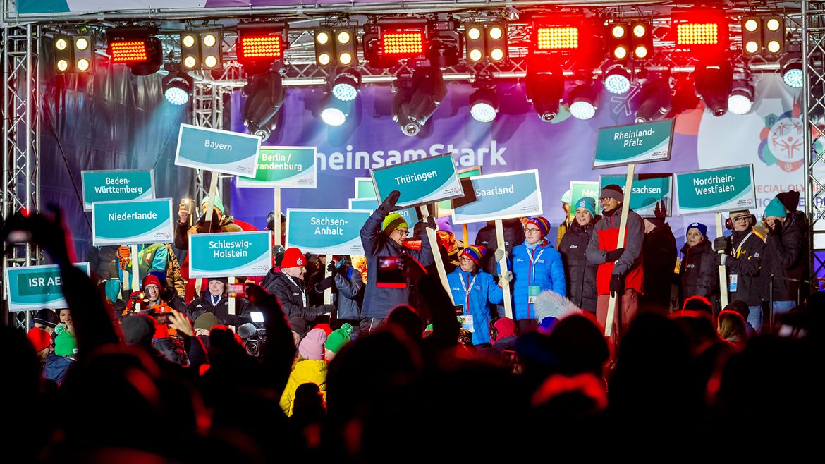Athleten und Athletinnen der 16 Landesverbände stehen auf der Bühne. Einige tragen Schilder mit den Namen der Bundesländer.